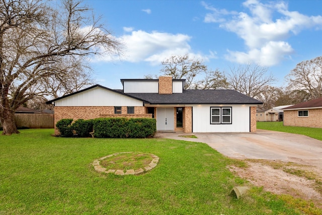 view of front of house featuring brick siding, a chimney, concrete driveway, a front yard, and fence