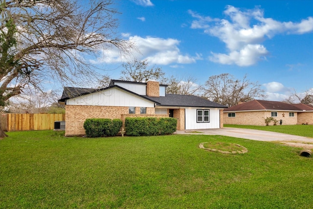 view of front of property featuring a front yard, concrete driveway, brick siding, and fence