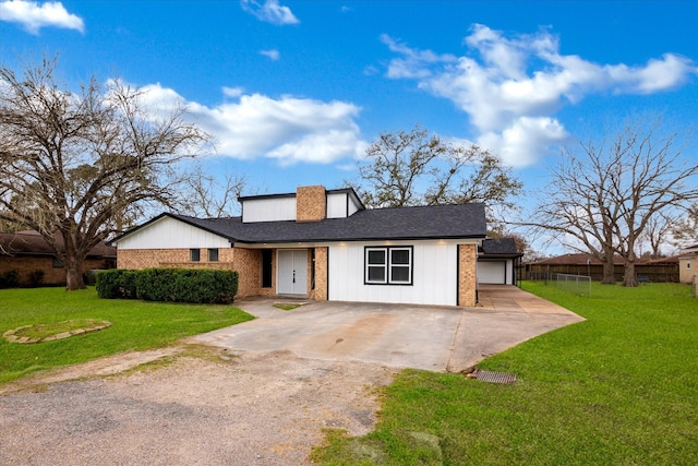 view of front of house with a front yard, concrete driveway, and brick siding