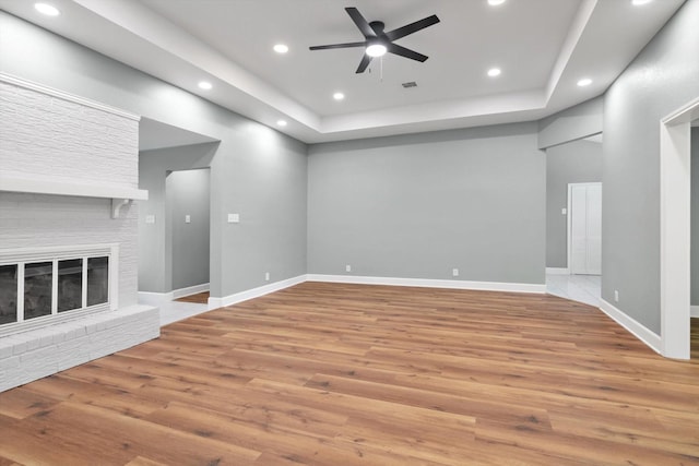 unfurnished living room featuring recessed lighting, a ceiling fan, a brick fireplace, wood finished floors, and baseboards