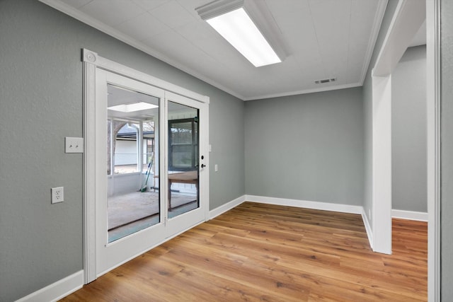 empty room with baseboards, visible vents, ornamental molding, and wood finished floors