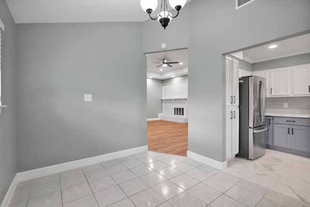 kitchen with light countertops, decorative backsplash, freestanding refrigerator, white cabinets, and baseboards