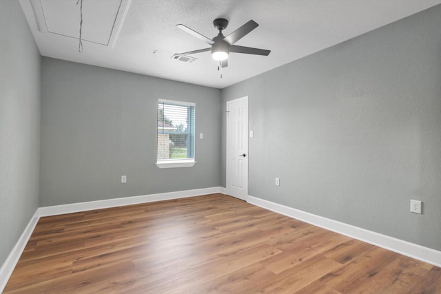 unfurnished room with baseboards, wood finished floors, visible vents, and attic access