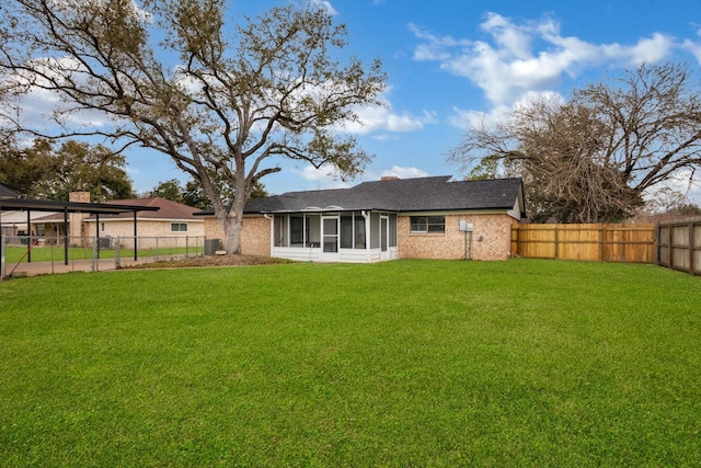 back of property with a sunroom, a fenced backyard, and a yard