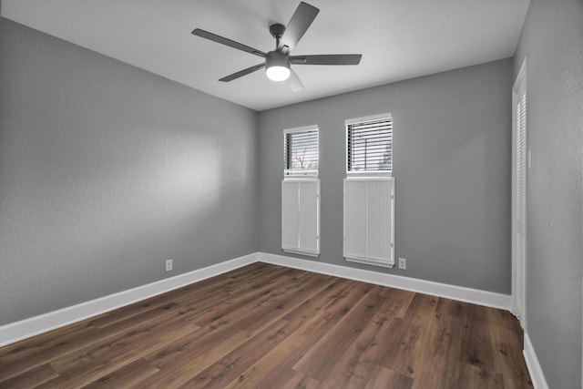 spare room featuring dark wood-style flooring, ceiling fan, and baseboards