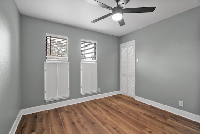 unfurnished room with dark wood-style floors, ceiling fan, and baseboards