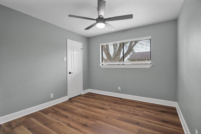 spare room featuring baseboards, dark wood finished floors, and a ceiling fan