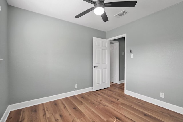 unfurnished room featuring baseboards, visible vents, ceiling fan, and wood finished floors