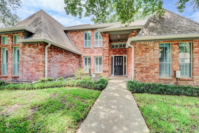 view of front of property featuring a shingled roof and brick siding