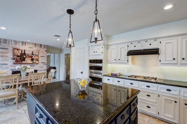 kitchen featuring dark stone counters, stainless steel appliances, hanging light fixtures, and white cabinetry