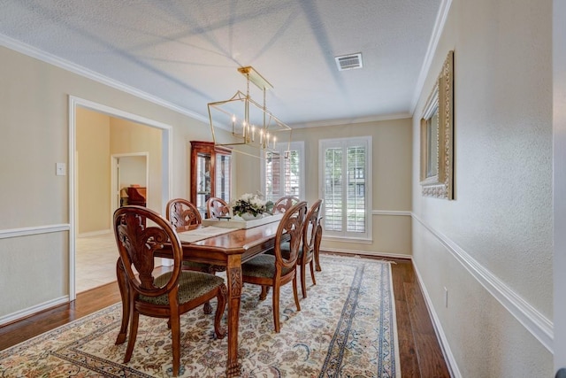 dining area with visible vents, crown molding, a textured ceiling, and wood finished floors