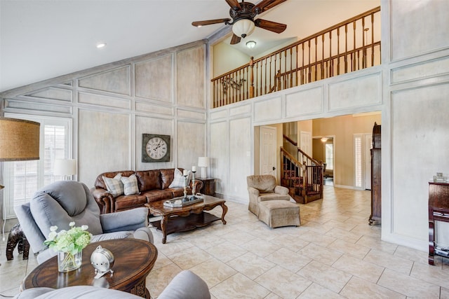 living area featuring light tile patterned floors, lofted ceiling, ceiling fan, stairs, and a decorative wall