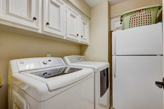 washroom with washer and dryer, cabinet space, and a textured ceiling