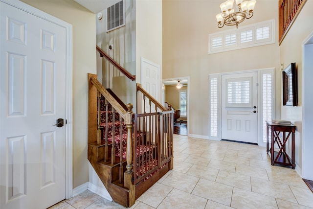 entryway with baseboards, visible vents, an inviting chandelier, a high ceiling, and stairs