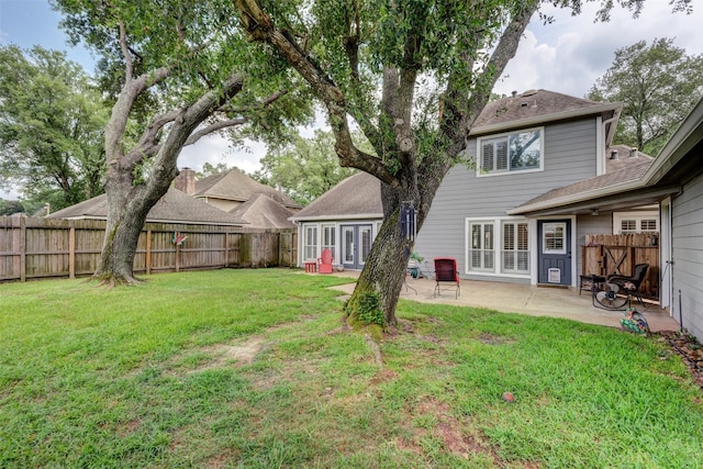 view of yard with a fenced backyard, a patio, and french doors