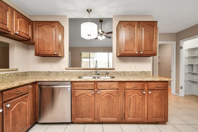 kitchen with stainless steel dishwasher, brown cabinetry, a sink, and light stone countertops