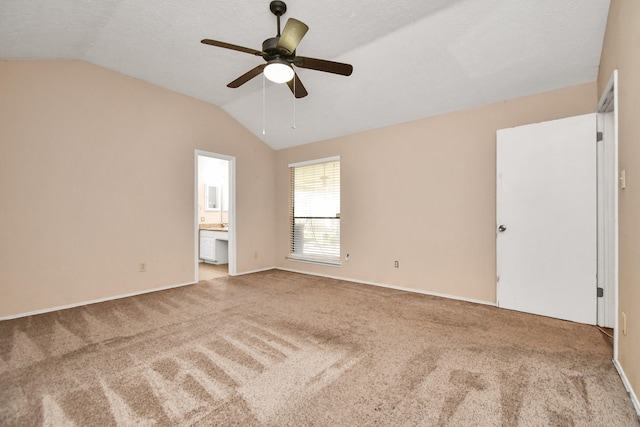 unfurnished bedroom featuring a ceiling fan, lofted ceiling, carpet flooring, and ensuite bathroom