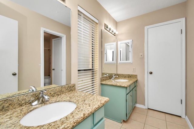 full bathroom with two vanities, a sink, baseboards, and tile patterned floors