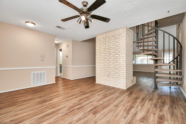 unfurnished room with a textured ceiling, wood finished floors, and visible vents