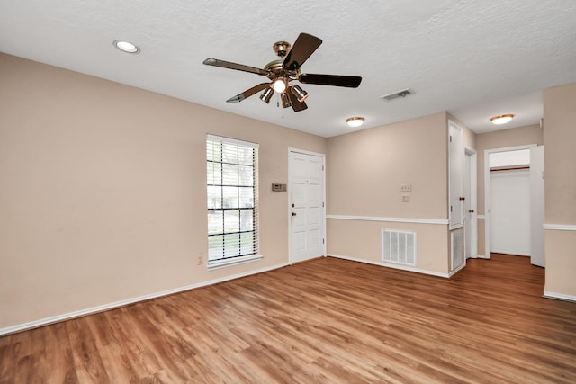 empty room with a textured ceiling, light wood finished floors, and visible vents