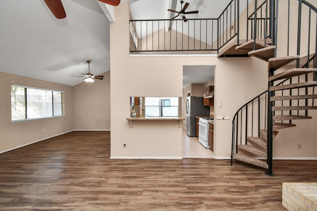 unfurnished living room with light wood-type flooring, ceiling fan, and stairs