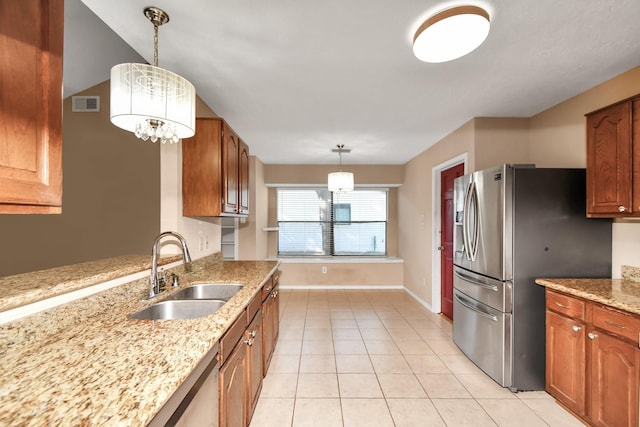 kitchen with light tile patterned floors, a sink, visible vents, brown cabinetry, and stainless steel fridge