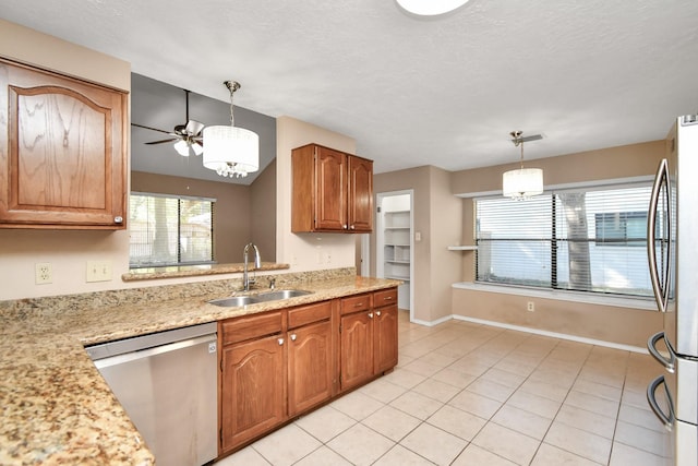 kitchen featuring baseboards, appliances with stainless steel finishes, pendant lighting, a sink, and light tile patterned flooring