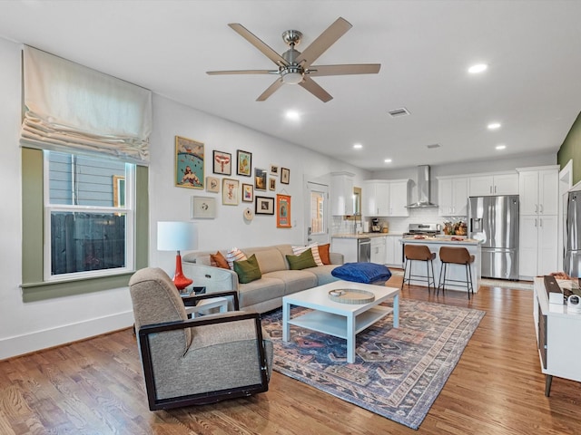 living room featuring a ceiling fan, recessed lighting, visible vents, and light wood-style flooring