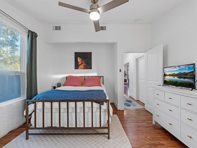 bedroom with ceiling fan, dark wood finished floors, and visible vents