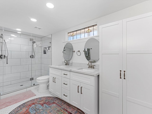 bathroom with toilet, a stall shower, a sink, and visible vents