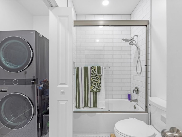 bathroom featuring toilet, stacked washer and dryer, and shower / bath combination with glass door