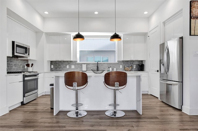 kitchen featuring stainless steel appliances, a breakfast bar, white cabinetry, and modern cabinets