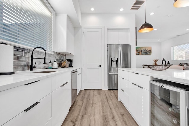 kitchen featuring beverage cooler, visible vents, modern cabinets, stainless steel appliances, and a sink