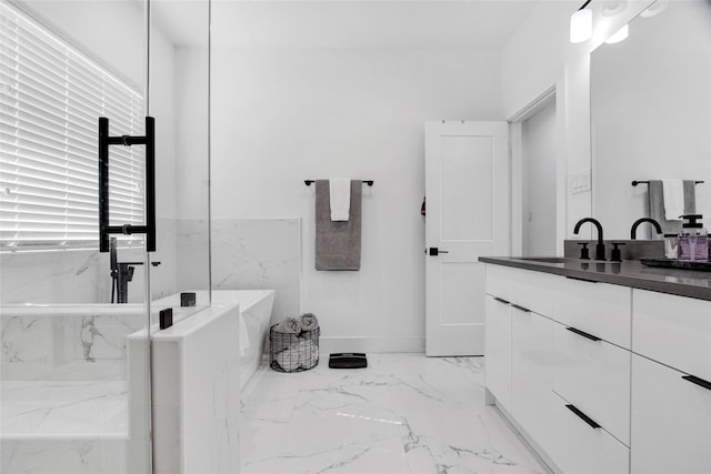 bathroom featuring marble finish floor, a soaking tub, vanity, and baseboards