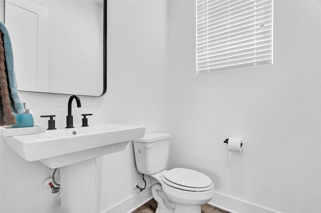 half bathroom with a sink, wood finished floors, toilet, and baseboards