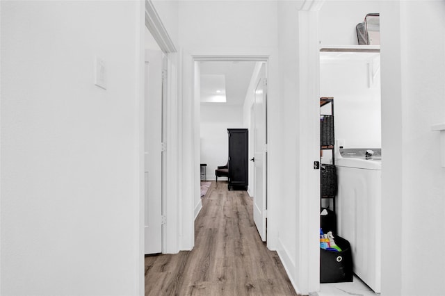 hallway with light wood finished floors and washer / clothes dryer