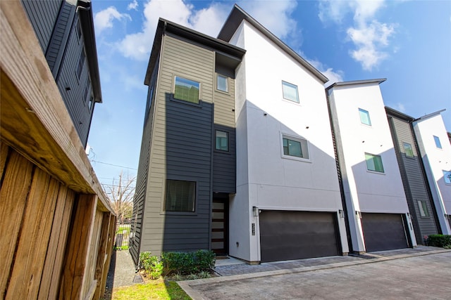 back of property featuring a garage, fence, and stucco siding