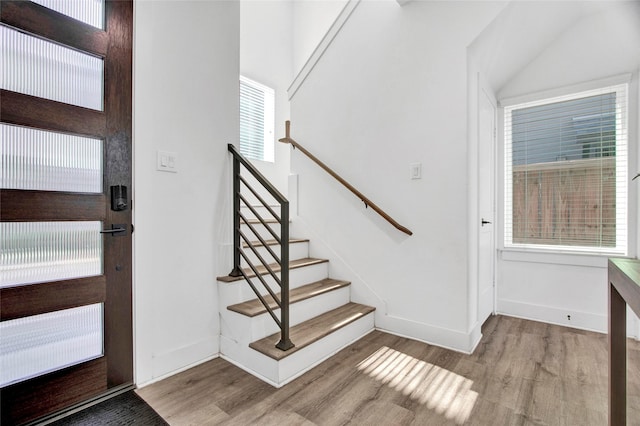 entryway with light wood-style floors, stairway, and baseboards