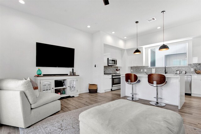 living area with light wood-style floors, recessed lighting, and visible vents