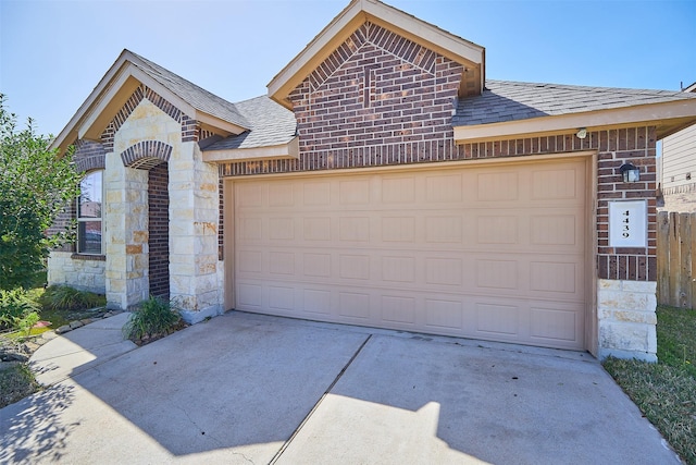 view of front of property featuring a garage, driveway, stone siding, roof with shingles, and brick siding