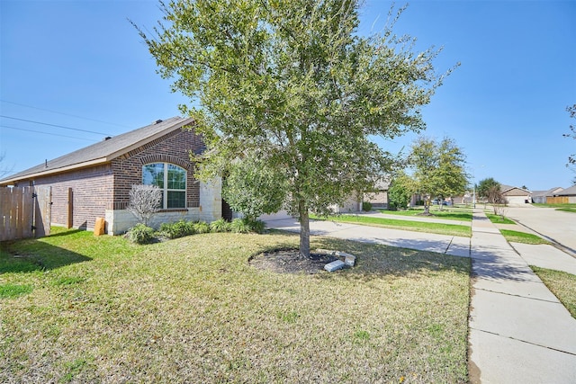 exterior space featuring a front yard, fence, and brick siding