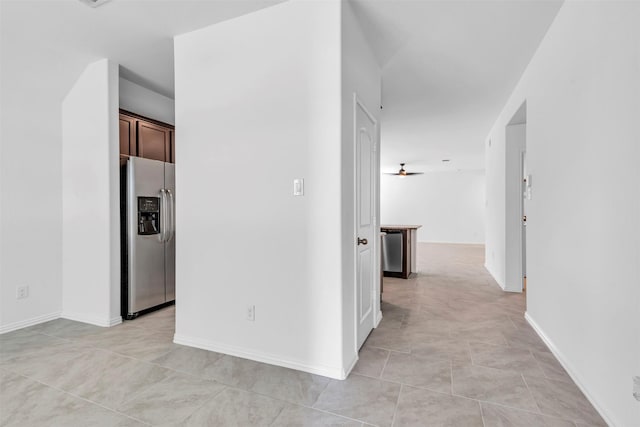 hall featuring light tile patterned floors and baseboards