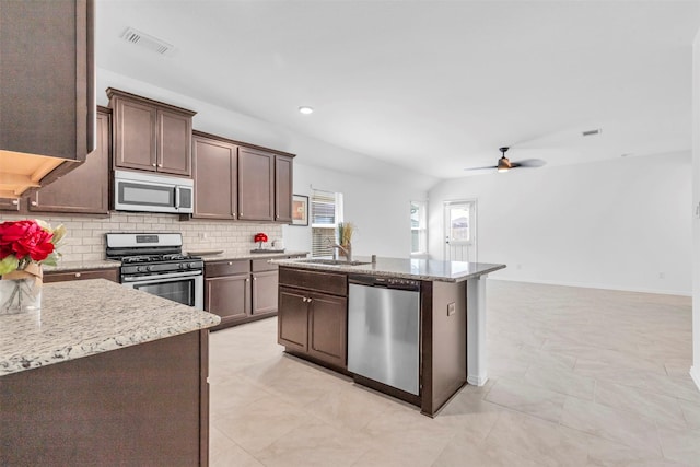 kitchen with visible vents, ceiling fan, a kitchen island with sink, stainless steel appliances, and backsplash