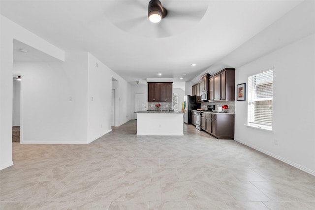 kitchen featuring backsplash, appliances with stainless steel finishes, open floor plan, ceiling fan, and dark brown cabinets