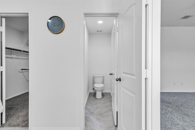 bathroom featuring baseboards, visible vents, a spacious closet, and toilet