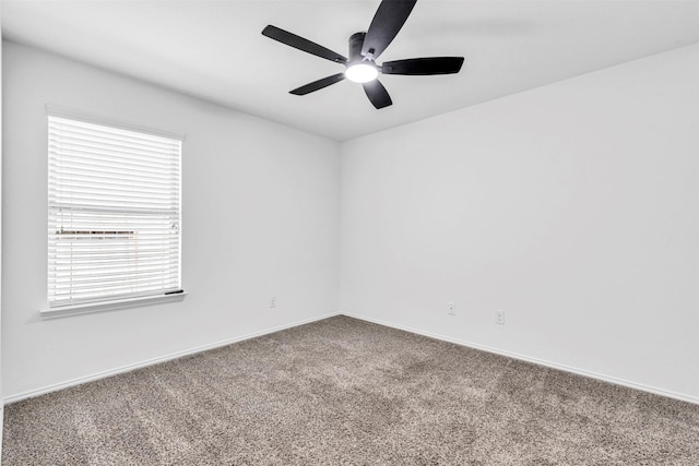 carpeted spare room with a ceiling fan and baseboards