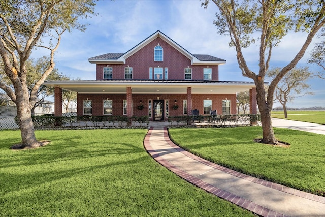 view of front of home with a standing seam roof, a front lawn, metal roof, and brick siding