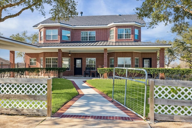 view of front of property featuring covered porch, brick siding, a standing seam roof, and a fenced front yard