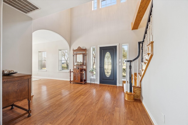 entryway with visible vents, light wood-style flooring, baseboards, and stairs