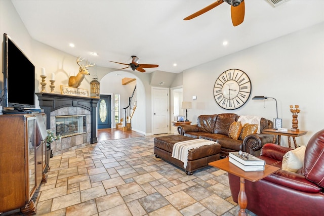 living room with recessed lighting, a ceiling fan, stairway, stone finish flooring, and a tiled fireplace